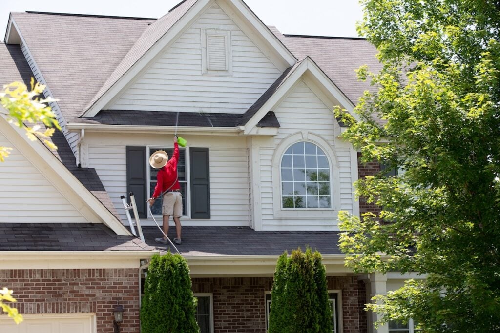 worker power washing asphalt roof